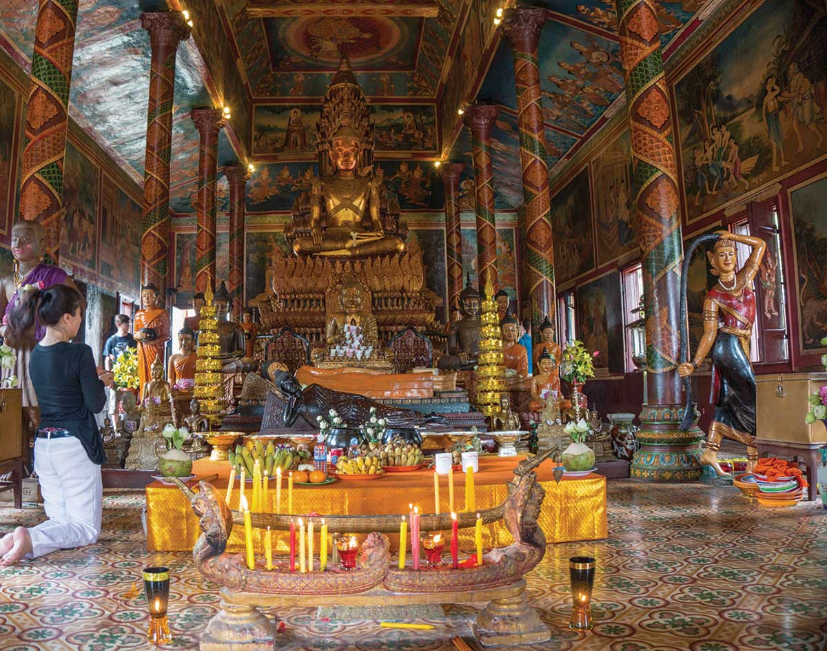 Inside of Wat Phnom temple where a large bronze Buddha resides over religious artifacts and effigies. COURTESY OF JIPE7. LICENSED UNDER CREATIVE COMMONS ATTRIBUTION 2.0 GENERIC.